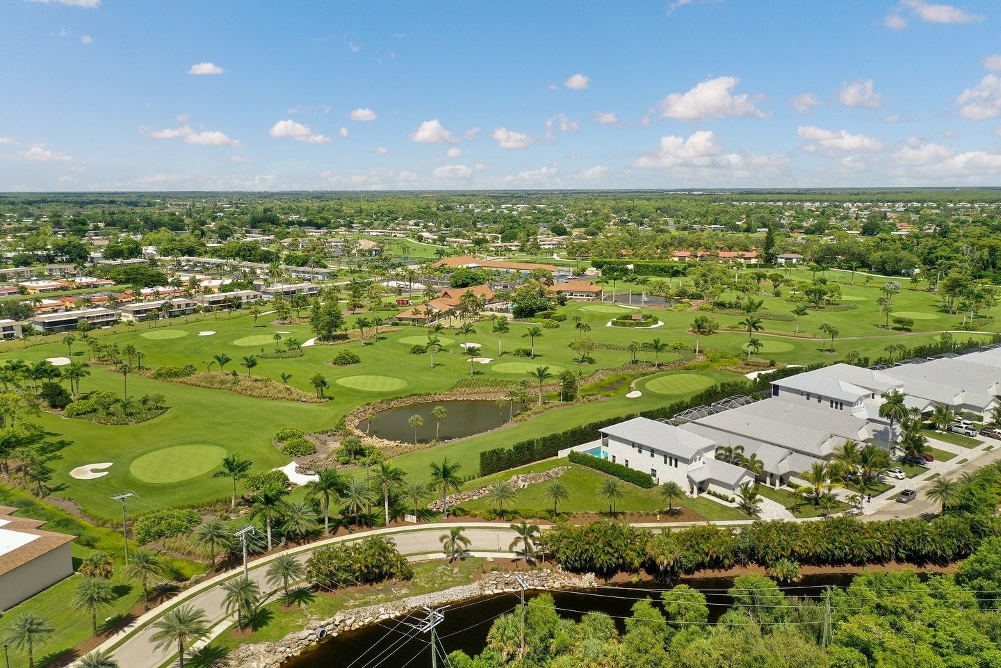 Aerial drone view of new white metal-roof homes beside a golf course