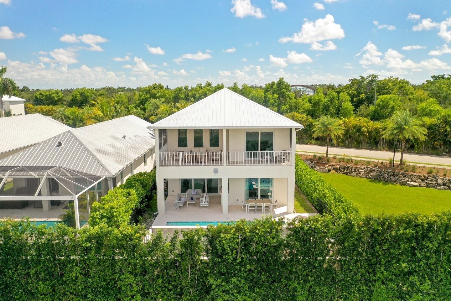 Drone view of the rear of a two-story home with balcony and pool
