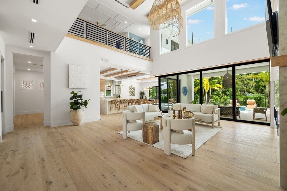 Double-height great room with loft railing, rattan chandeliers and sliding glass doors