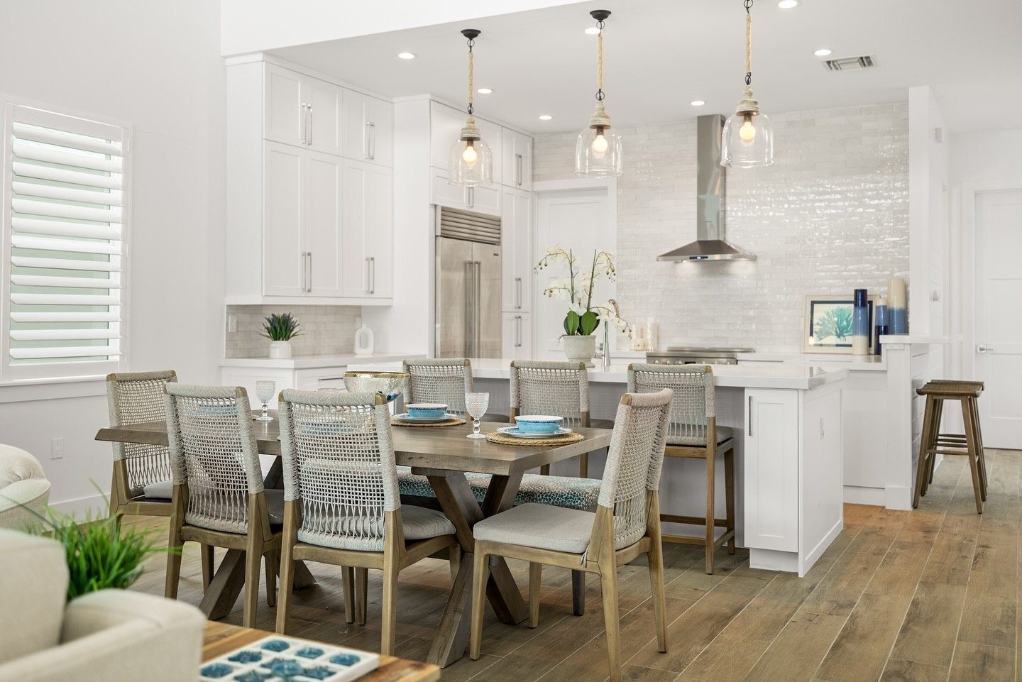 Dining table with rope chairs in front of a white kitchen