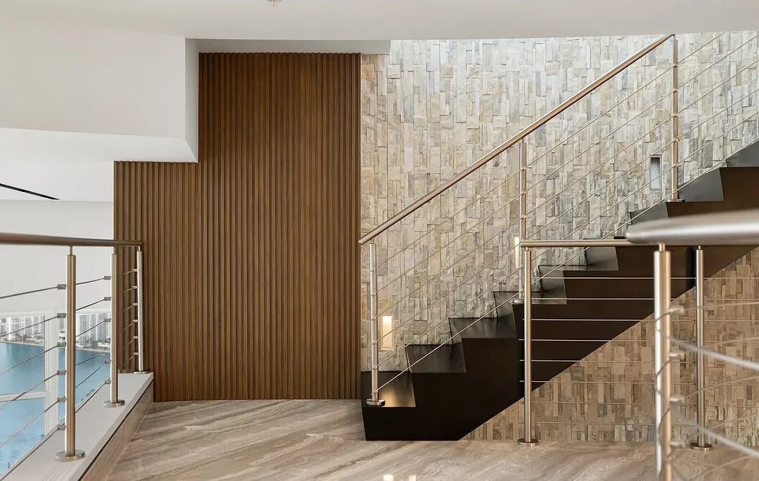 Floating stair against a stone wall with a water view