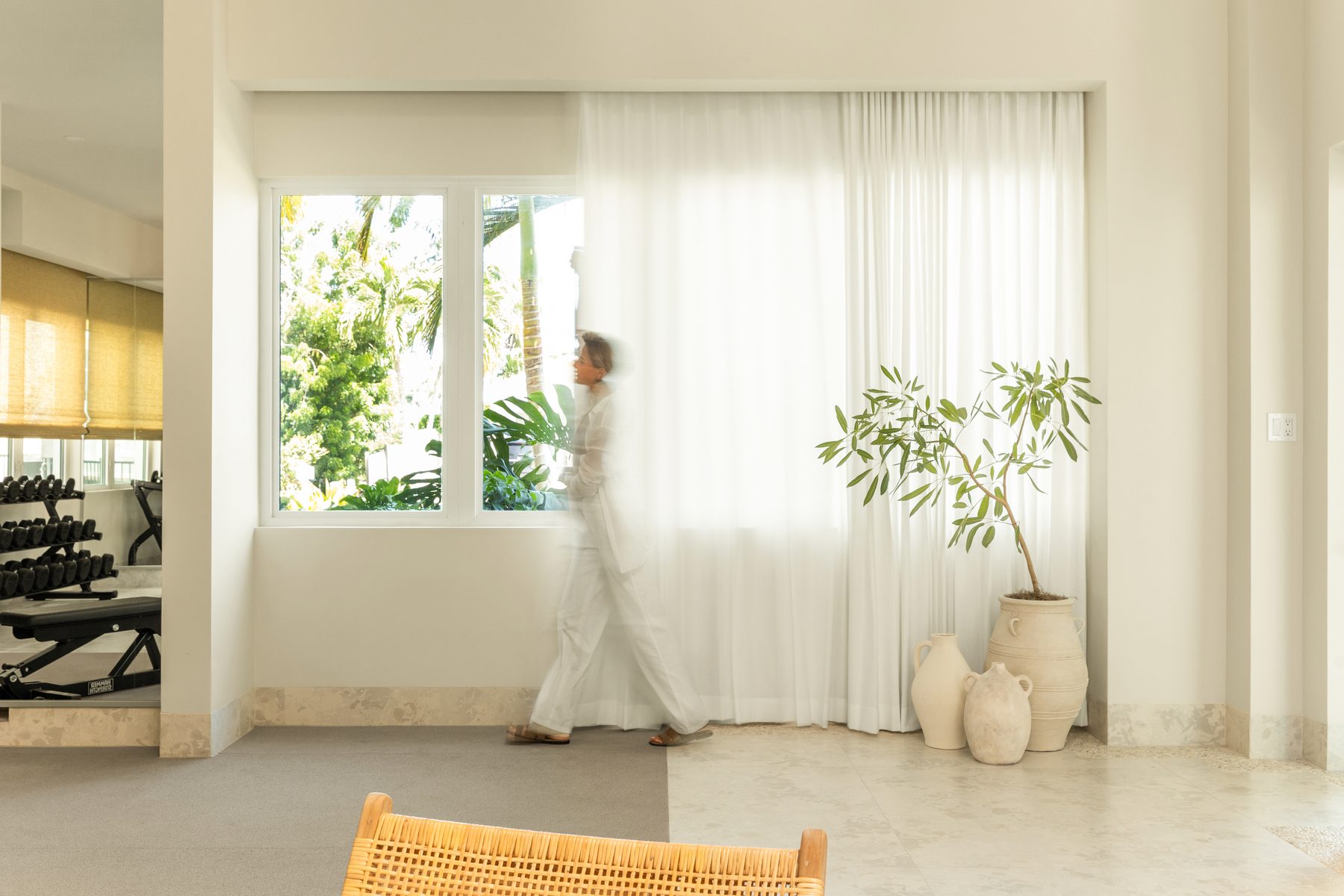 The designer walking past sheer curtains in the finished room