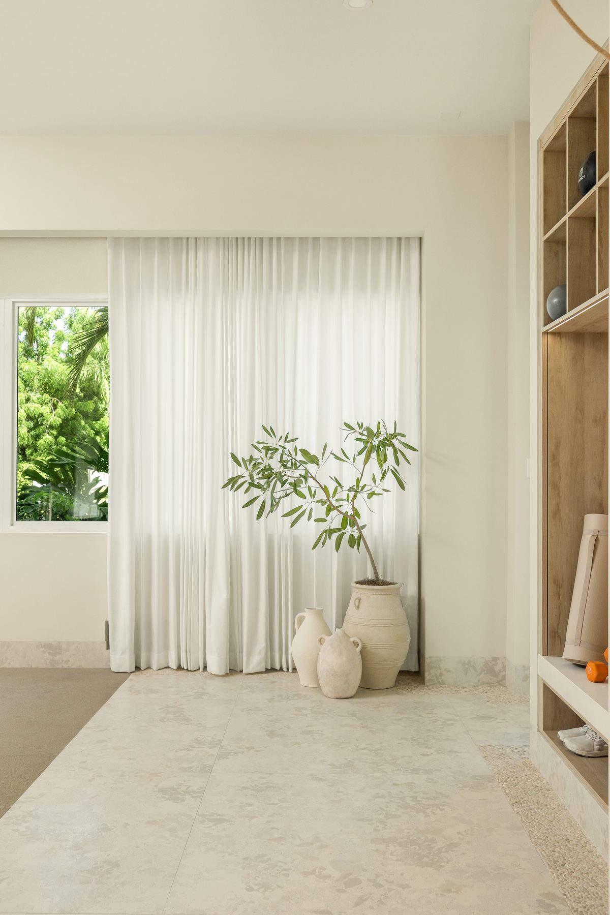 Sheer curtains, olive tree and clay vases in soft window light