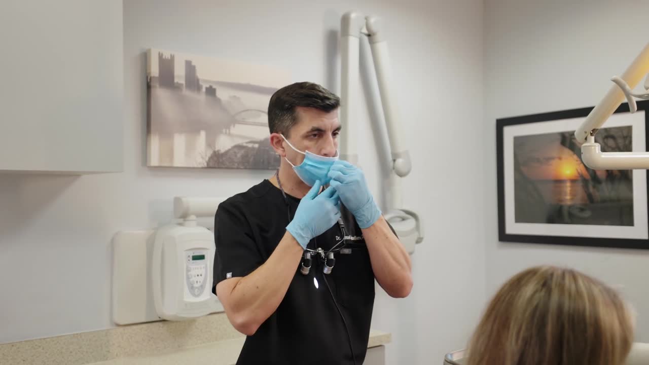 Dentist putting on gloves in a bright treatment room